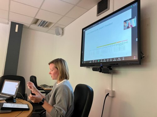 Fiona Hamilton presents her research, sitting at a desk with her slides showing on a screen