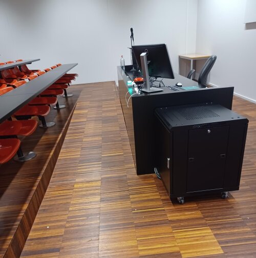Auditorium S.M.001: via het hellend vlak kom je tot bij de rolstoeltoegankelijke plaats.