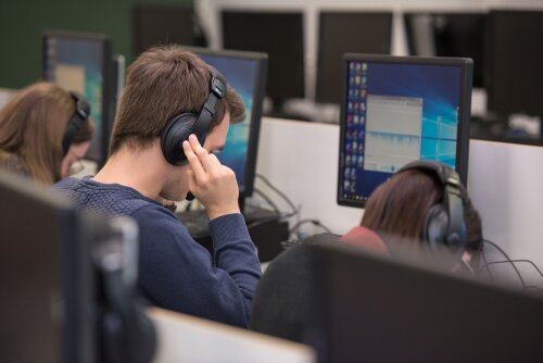 Student luistert in hoofdtelefoon om te kunnen vertalen op het computerscherm