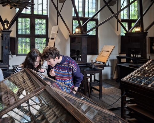 Twee studenten Nederlandse taal- en letterkunde bestuderen een letterkast in het Plantin-Moretusmuseum.